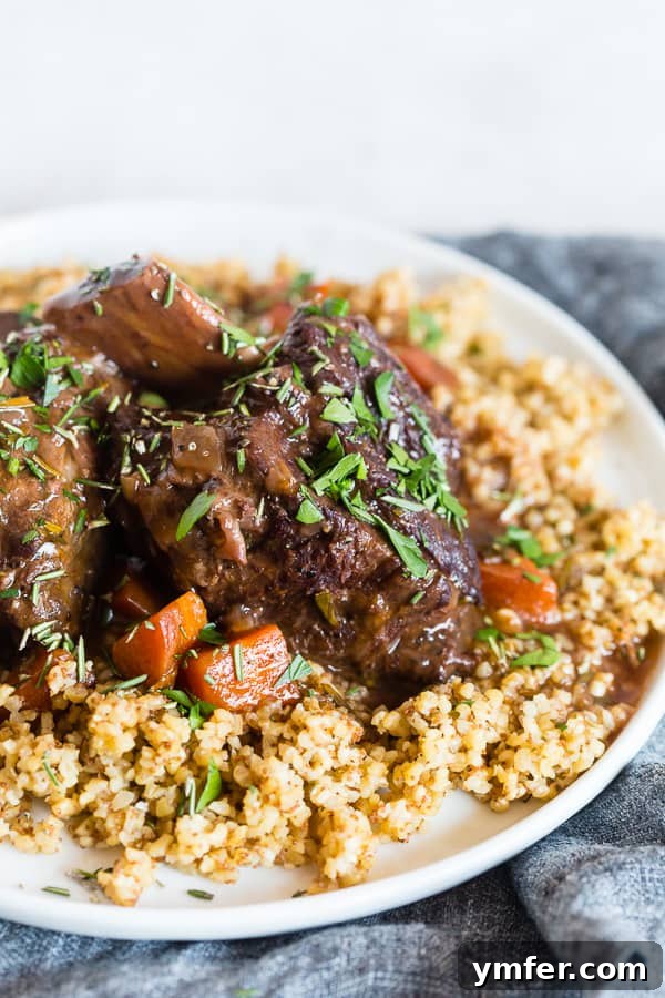 Succulent Red Wine Instant Pot Short Ribs 2 Perfectly tender Instant Pot Short Ribs with Red Wine and fresh rosemary on a plate, ready to be served over mashed potatoes.
