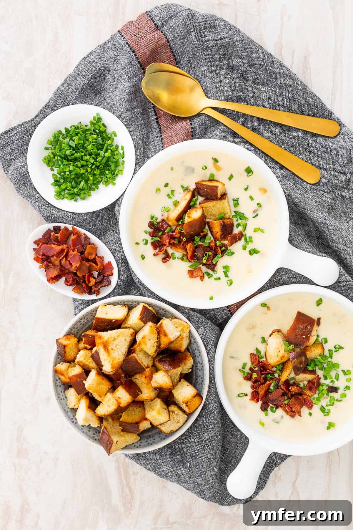 Champion Beer Cheese Soup 4 Two bowls of Beer Cheese Soup arranged on a rustic wooden table with small plates of crispy bacon, chives, and pretzel croutons on the side for topping.
