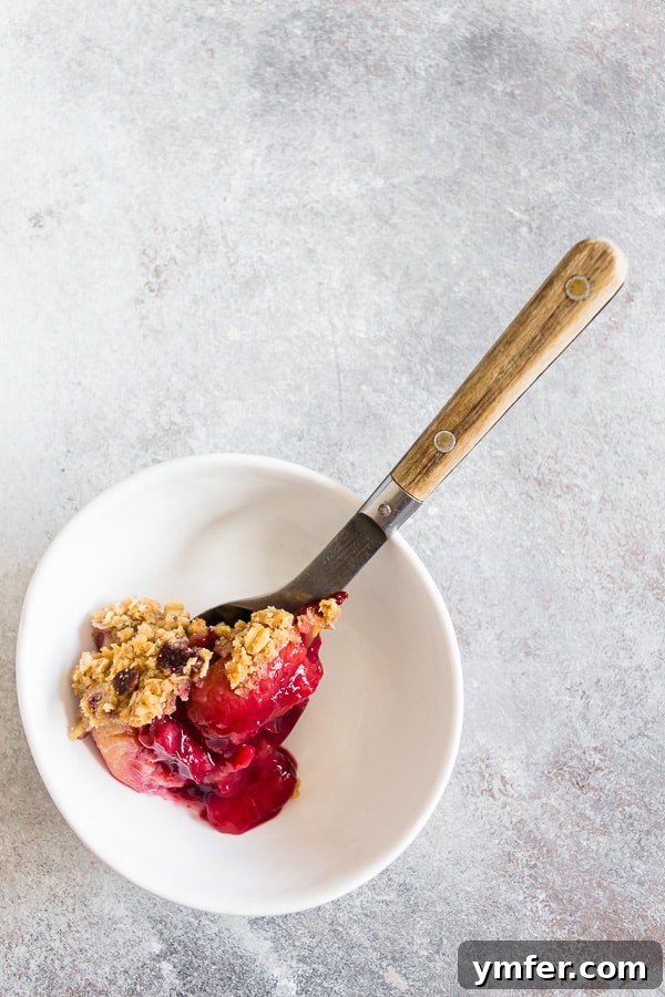 Cardamom Plum Crisp with Vanilla Bean 4 Cardamom Vanilla Plum Crisp spooned into a small white bowl, ready to be enjoyed.