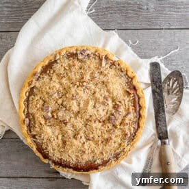 A festive apple butter pumpkin pie with a streusel topping, perfect for holiday gatherings.