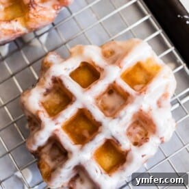 Glazed apple butter waffle donuts cooling on a wire rack.