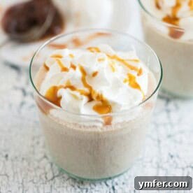 A rich, boozy caramel apple butter milkshake in a tall glass.