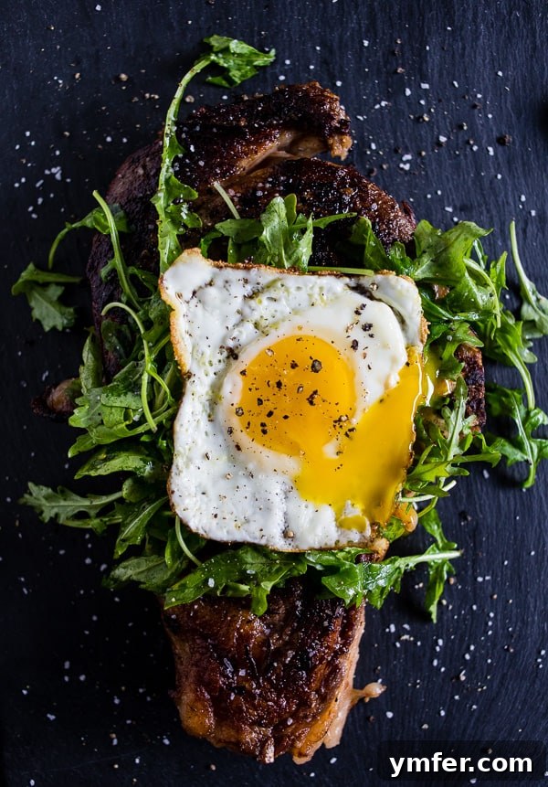 Golden Yolk Seared Ribeye 3 fried egg topped grilled steak with arugula leaves under the egg