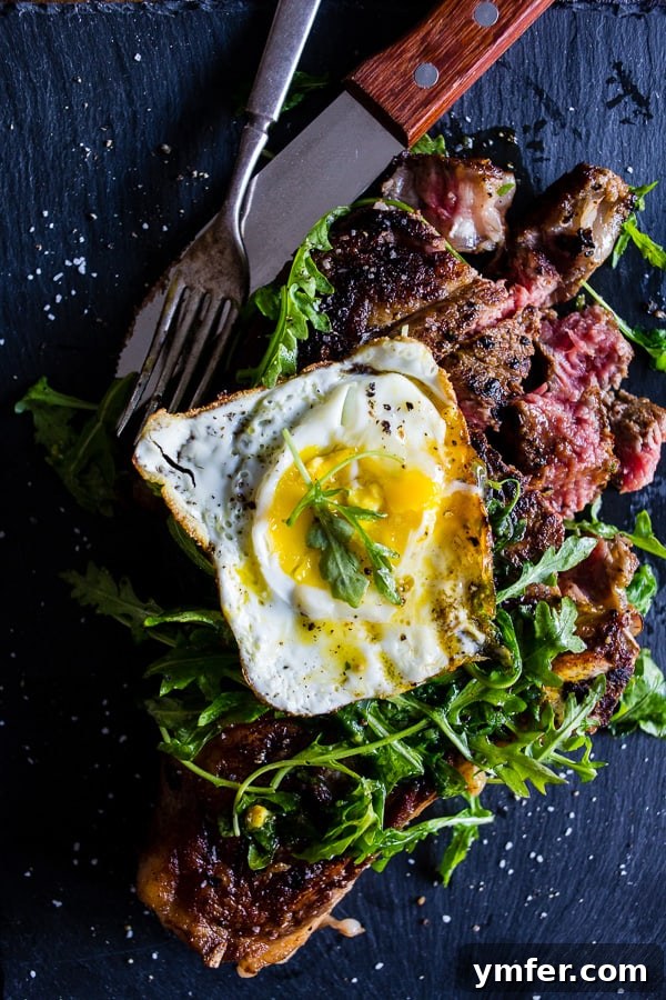 Golden Yolk Seared Ribeye 4 fried egg topped grilled ribeye steak with arugula salad sitting on a black plate