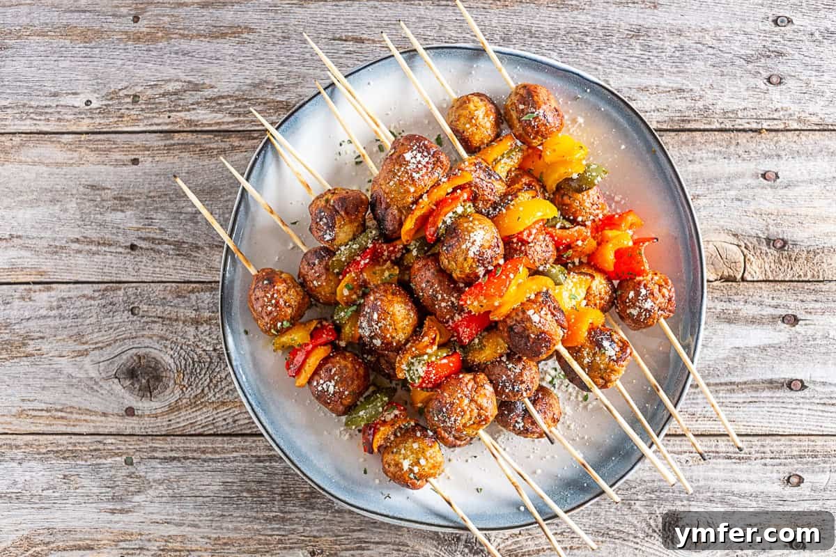 Fire-Kissed Chicken Meatball Skewers 5 Two grilled chicken meatball skewers arranged neatly on a small white plate.