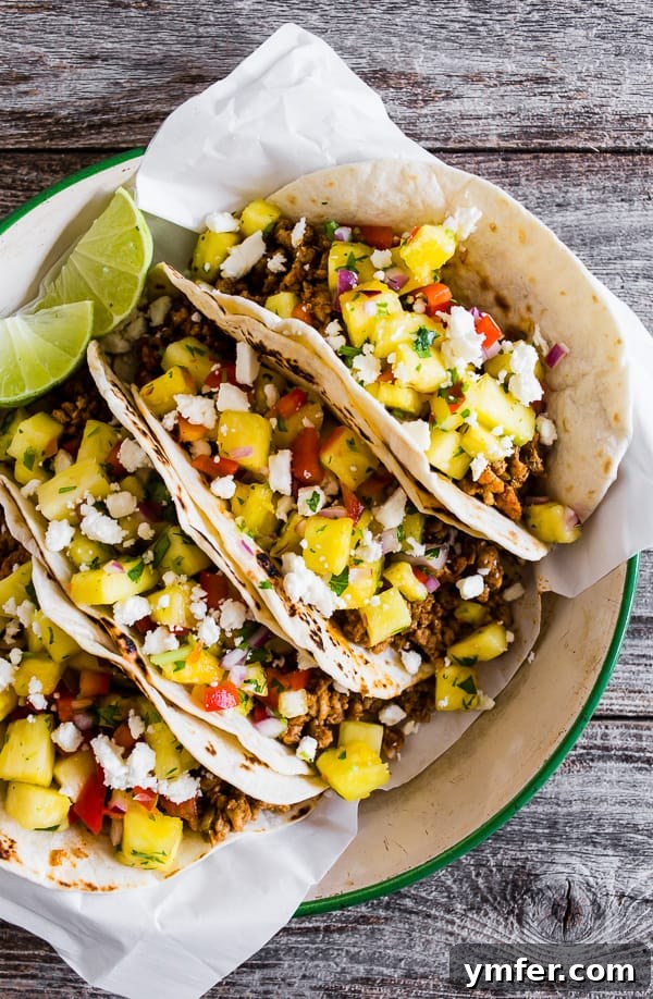 Aloha Pork Tacos with Pineapple Salsa 2 Juicy ground pork tacos topped with fresh, colorful pineapple salsa, ready to be enjoyed.