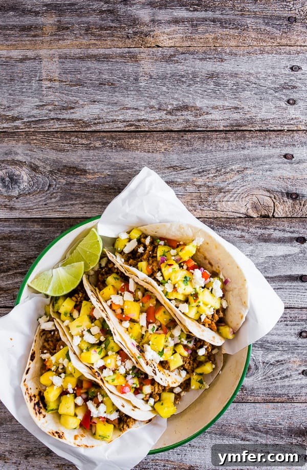 Aloha Pork Tacos with Pineapple Salsa 5 Multiple ground pork tacos topped with pineapple salsa, arranged in a rustic setting.