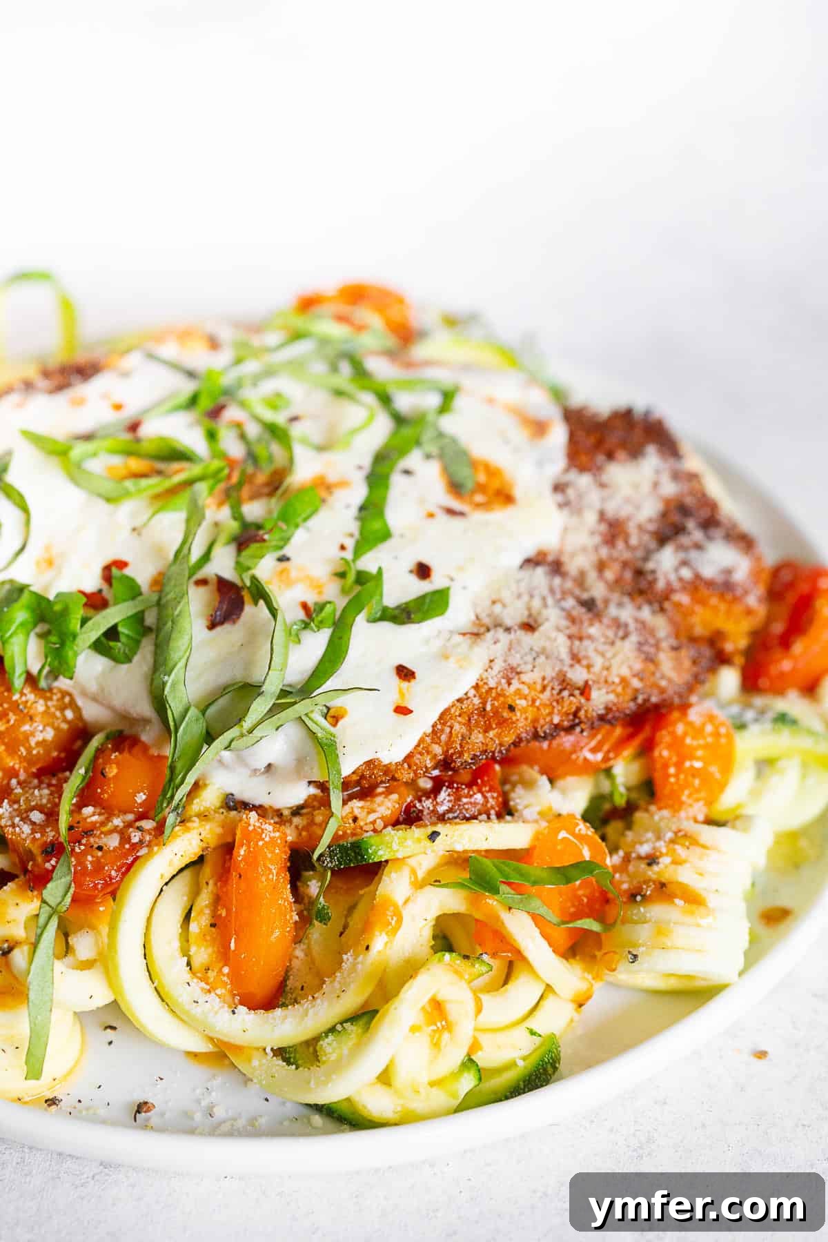 Summertime Zucchini Noodle Chicken Parm 2 Crispy Summer Chicken Parmesan with Zoodles on a plate, garnished with fresh basil.