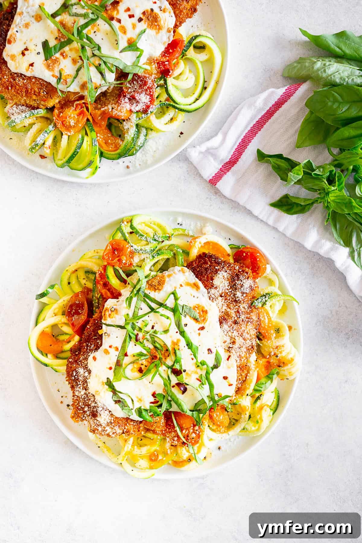 Summertime Zucchini Noodle Chicken Parm 3 Summer Chicken Parmesan with Zoodles garnished with fresh basil on a white plate.