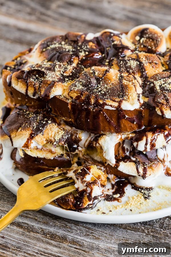 Gooey Smores French Toast 7 A fork taking a bite out of S'mores French toast, showing the gooey marshmallow and chocolate.