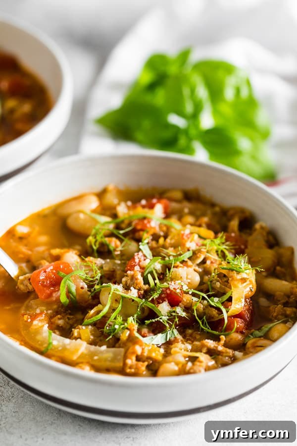 Italian Sausage Fennel White Bean Soup garnished with fresh basil leaves.