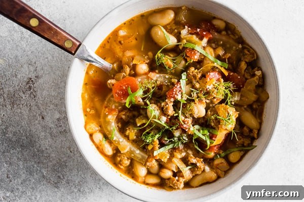 Italian Sausage Fennel White Bean Soup topped with grated Parmesan cheese and basil.