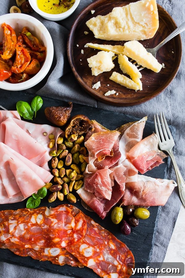 Cured meats, nuts, roasted tomatoes, and cheese on a board.