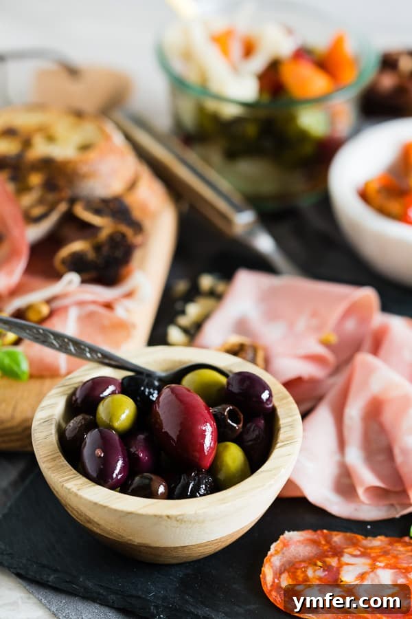 Bowl of olives with cured meats on a charcuterie board.