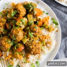 Delicious Red Curry Turkey Meatballs served in a bowl with rice and garnished with green onions.