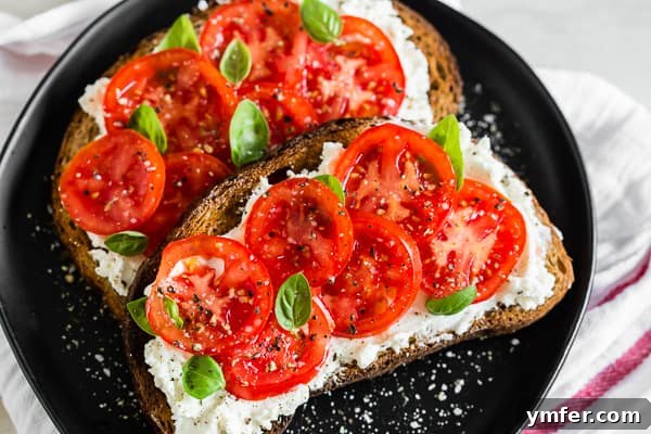 Tuscan Morning Toast 5 A serving of tomato ricotta toast, garnished with fresh basil, salt, and pepper, presented on a white plate.