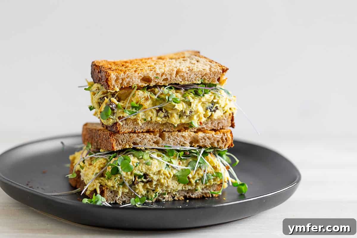 Zesty Curried Greek Yogurt Chicken Salad 6 curried chicken salad on toasted bread cut in half. A close-up of a curried chicken salad sandwich on toasted bread, cut in half to reveal its rich, colorful filling.