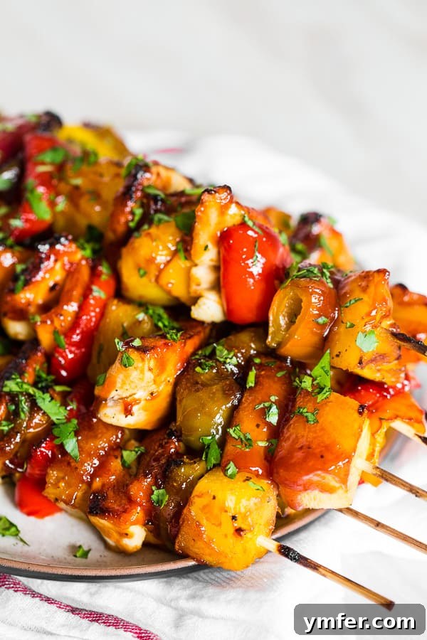 Island Pineapple Chicken Skewers 2 Pineapple Chicken Kebabs sitting on a serving plate, vibrant and ready to eat.