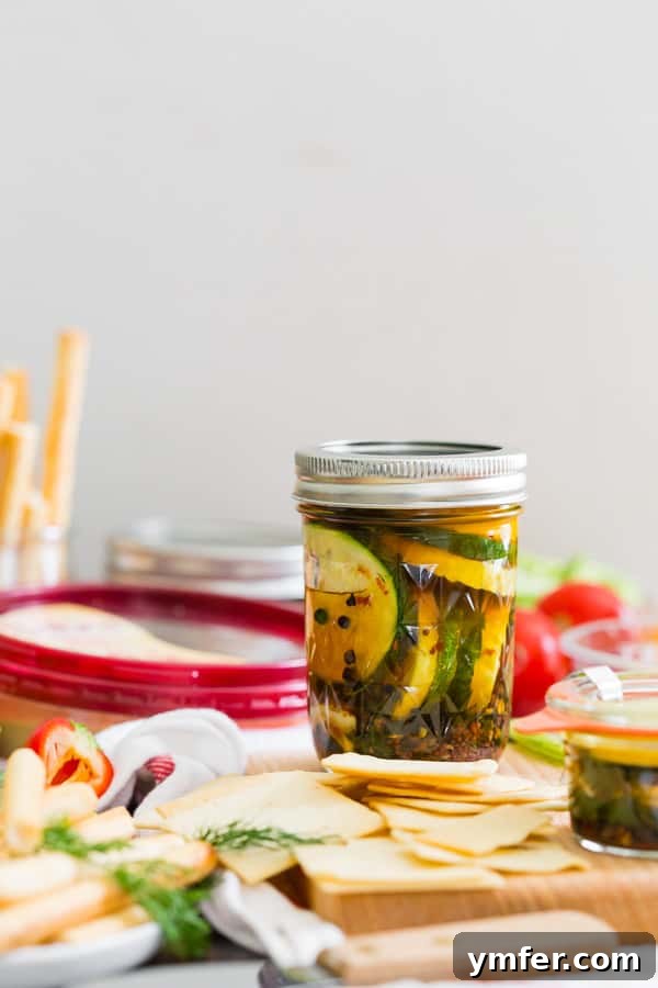 Zesty Zucchini Zingers 6 A glass jar of sweet and spicy zucchini pickles resting on a colorful hummus and vegetable snack board, ready to be served as a party appetizer.