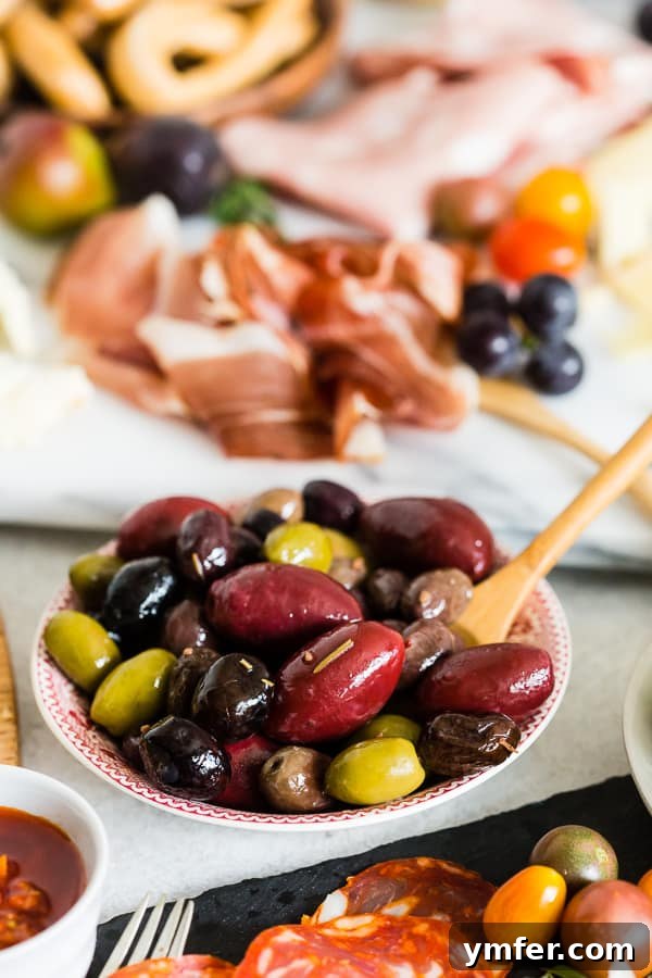 Gourmet Italian Antipasto Board 4 A charming bowl of juicy olives nestled among an assortment of authentic Italian cheeses, fruits, and crackers on an Ultimate Italian Antipasto Platter, emphasizing delightful contrasts.
