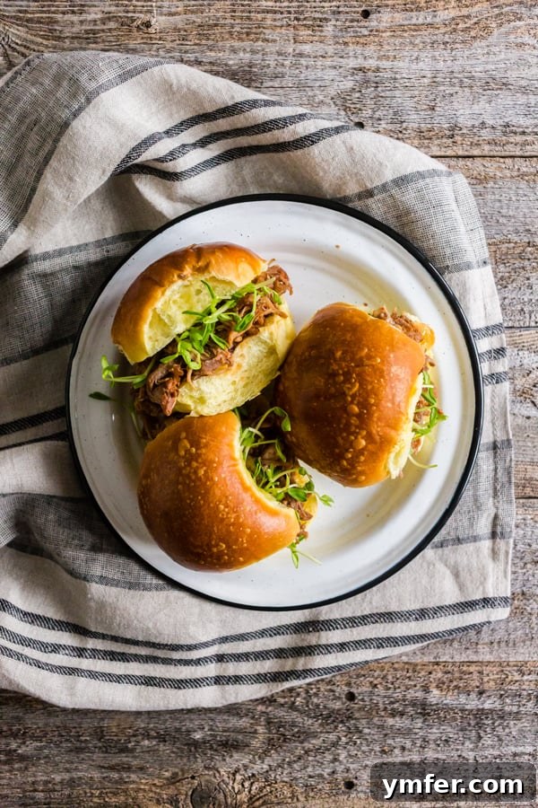 Cranberry Infused Instant Pot Pulled Pork 3 A perfectly assembled Instant Pot Cranberry Sauce Pulled Pork sandwich on a soft bun, garnished with fresh greens, ready to be enjoyed.