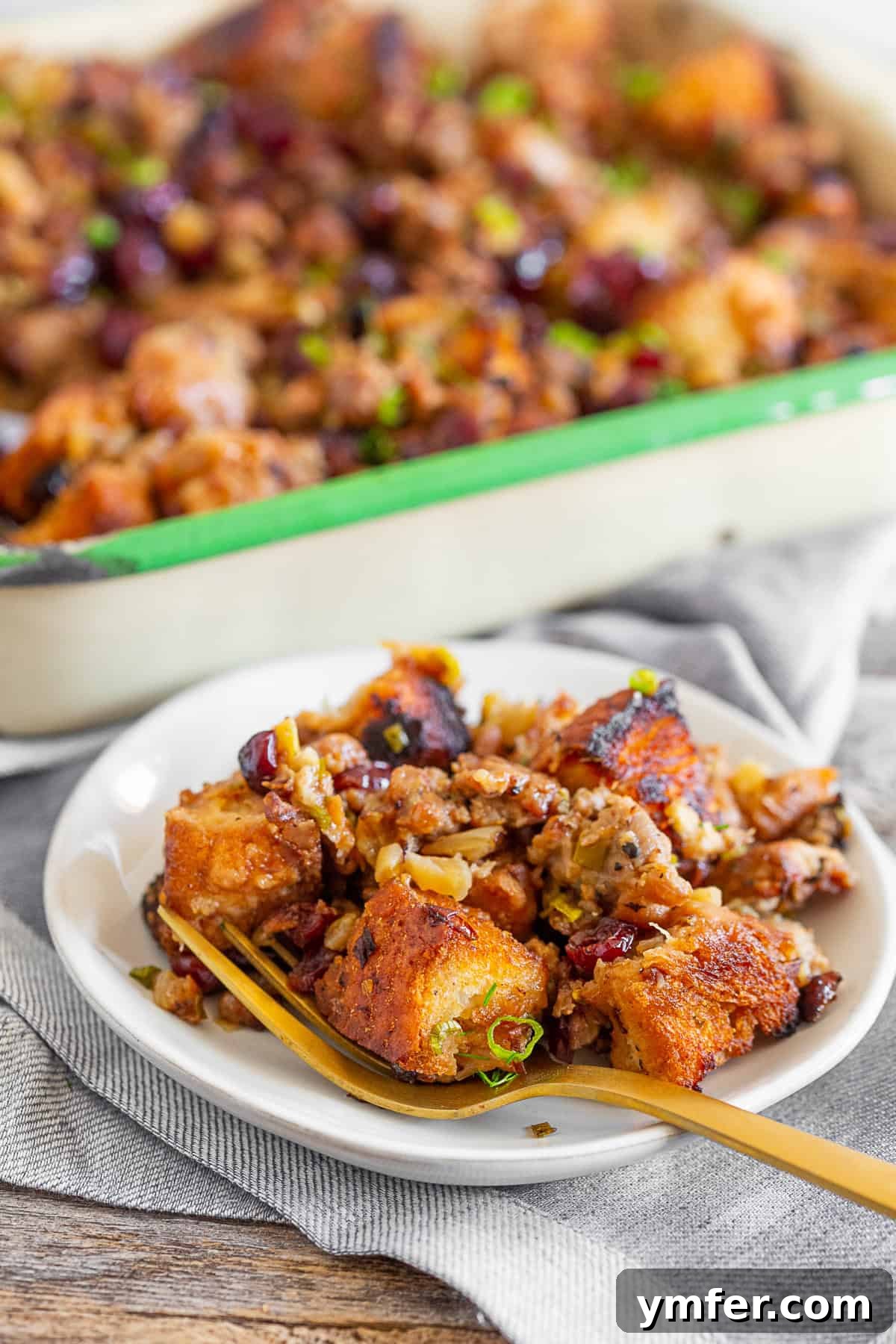 Buttery Texas Toast Dressing 3 A serving of Texas Toast Stuffing on a white plate, showcasing its rich texture and colorful ingredients.