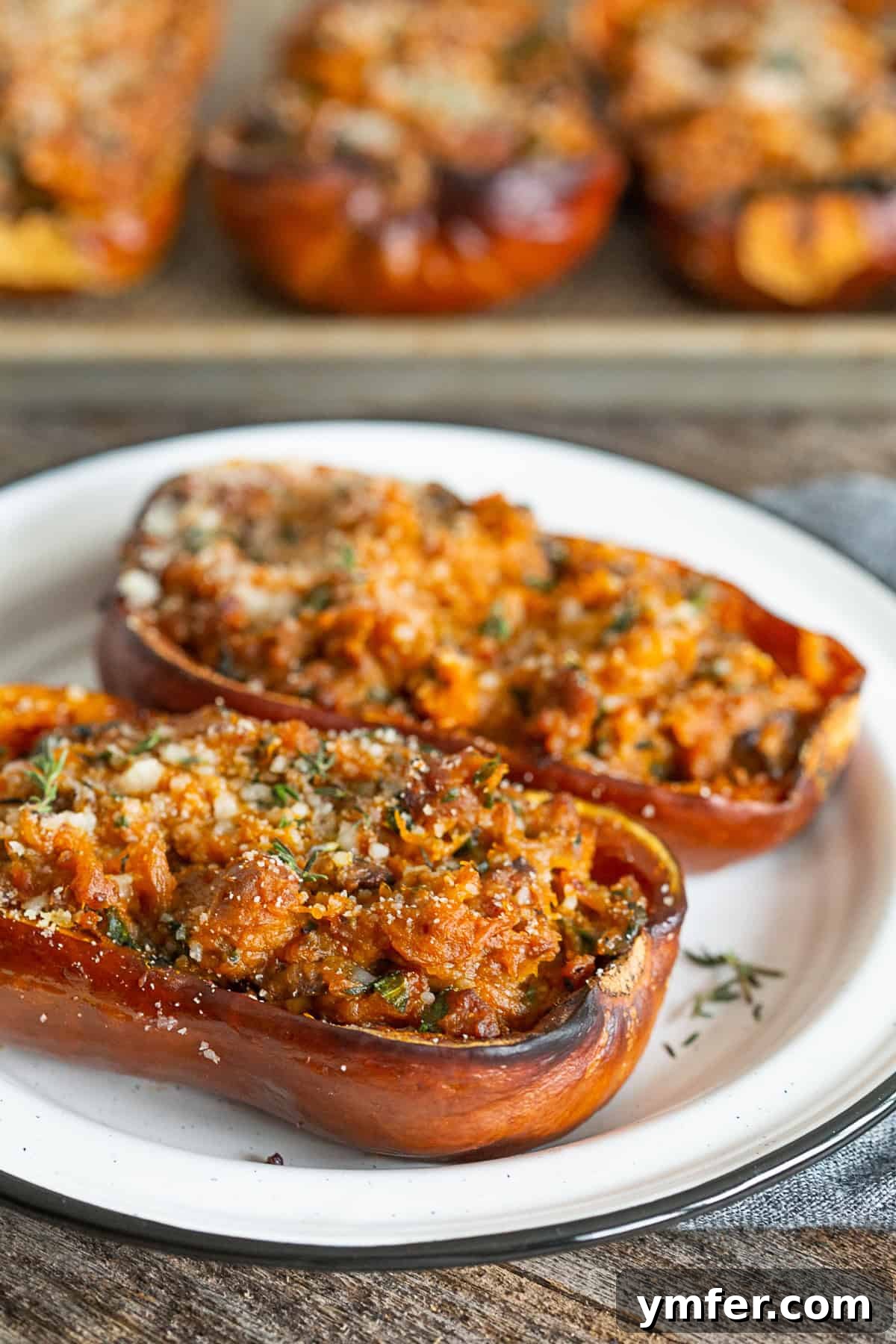 Savory Stuffed Honeynut Squash 2 Two halves of stuffed honeynut squash, generously filled with Italian sausage, mushrooms, and spinach, presented on a pristine white ceramic plate, ready to be enjoyed.