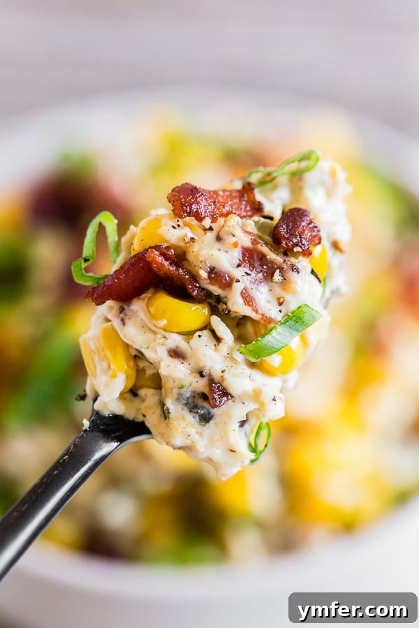 Zesty Bacon Creamy Corn Delight 4 A spoonful of Creamy Bacon Jalapeno Corn Dip being lifted from a white bowl.