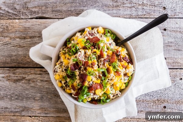 Zesty Bacon Creamy Corn Delight 5 Creamy Bacon Jalapeno Corn Dip in a bowl with a spoon, ready to be served.