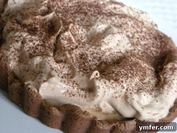 A close-up of the delicious layers of a Milky Way Tart. This sweet and creamy milky way tart gives you all the flavors of the candy bar in tart form. You're going to love all this chocolate and caramel goodness.