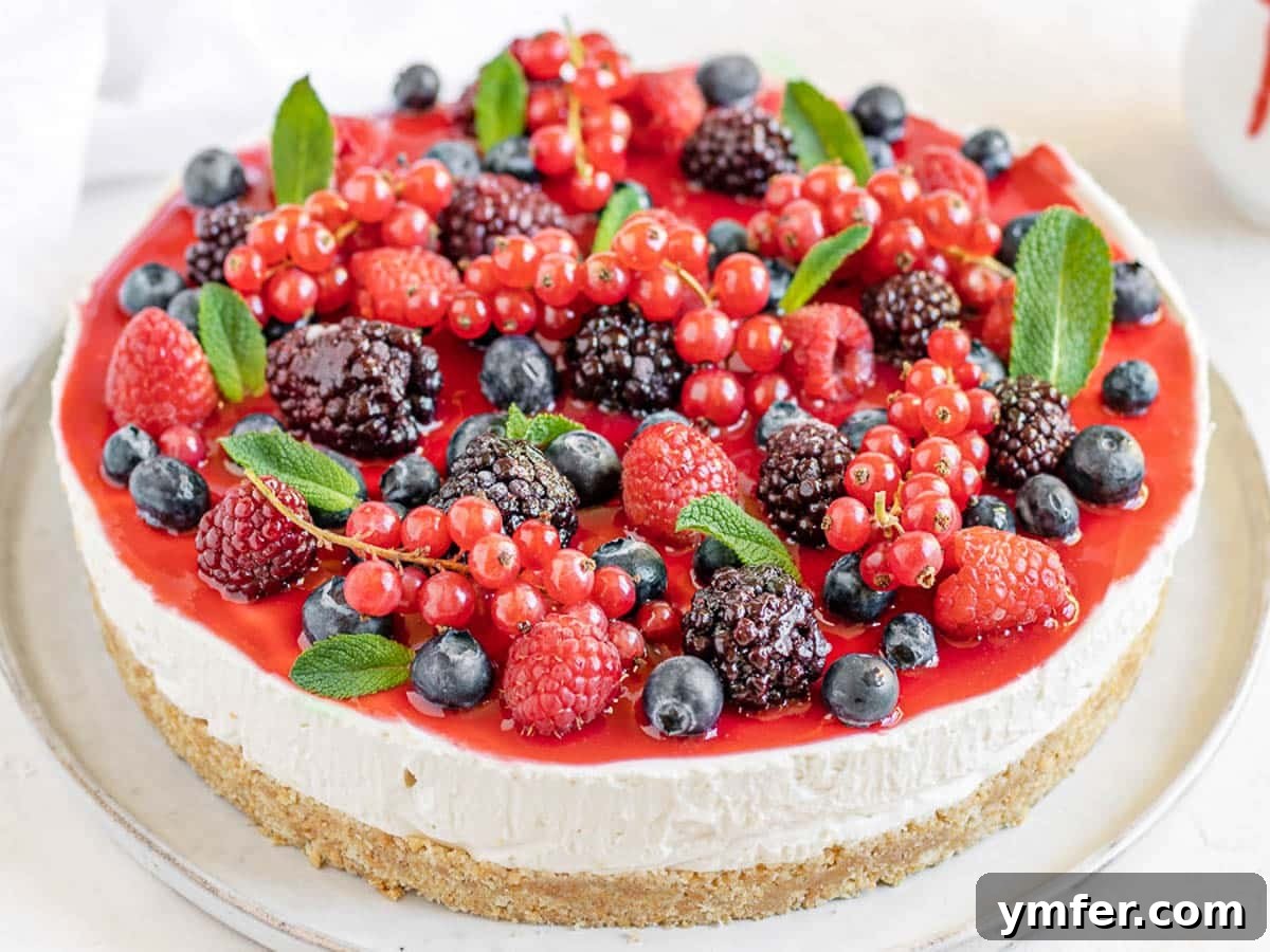 Creamy No-Bake Vegan Cheesecake 4 A vibrant vegan cheesecake topped with a medley of forest fruits and fresh mint leaves.