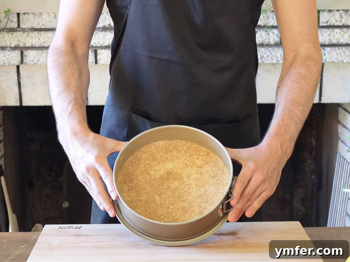 Creamy No-Bake Vegan Cheesecake 6 Vegan cheesecake biscuit crust being pressed into a cake pan, ready for chilling.