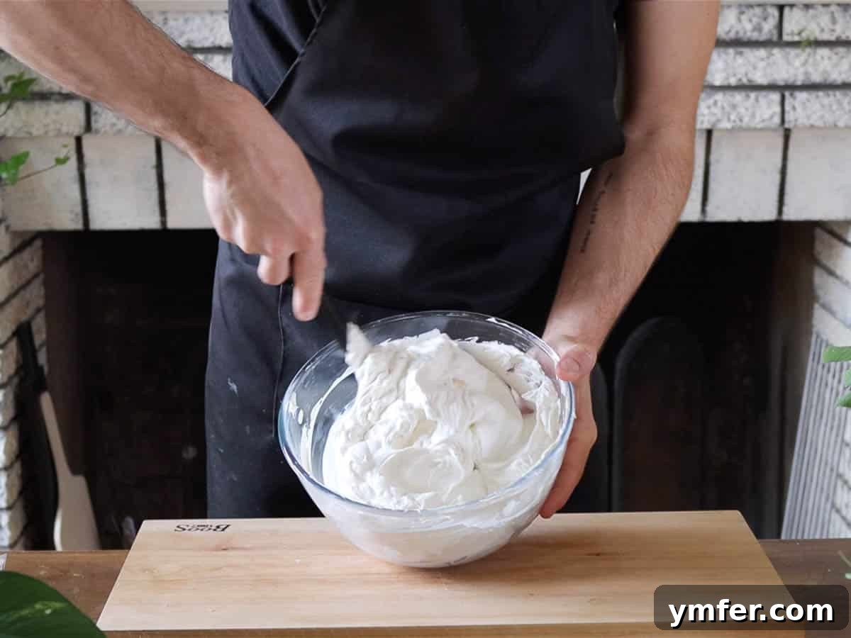 Creamy No-Bake Vegan Cheesecake 7 Hands expertly mixing the vegan cream cheese and whipped cream for the filling.