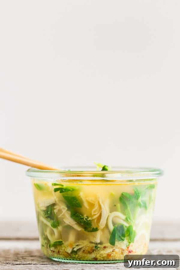 Instant Ramen Jars 2 A glass jar filled with homemade cup of noodles ingredients, with boiling water being poured in, releasing steam and preparing a quick, healthy meal.