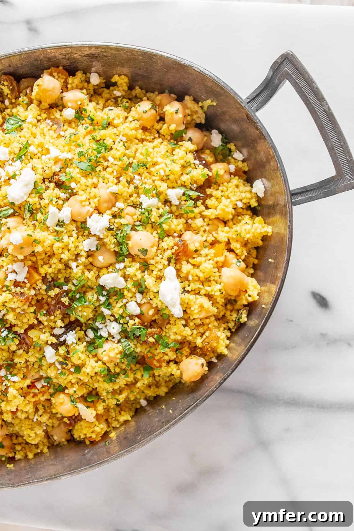 Vibrant Moroccan Chickpea Couscous 2 Moroccan Couscous in a baking dish, garnished with fresh herbs.