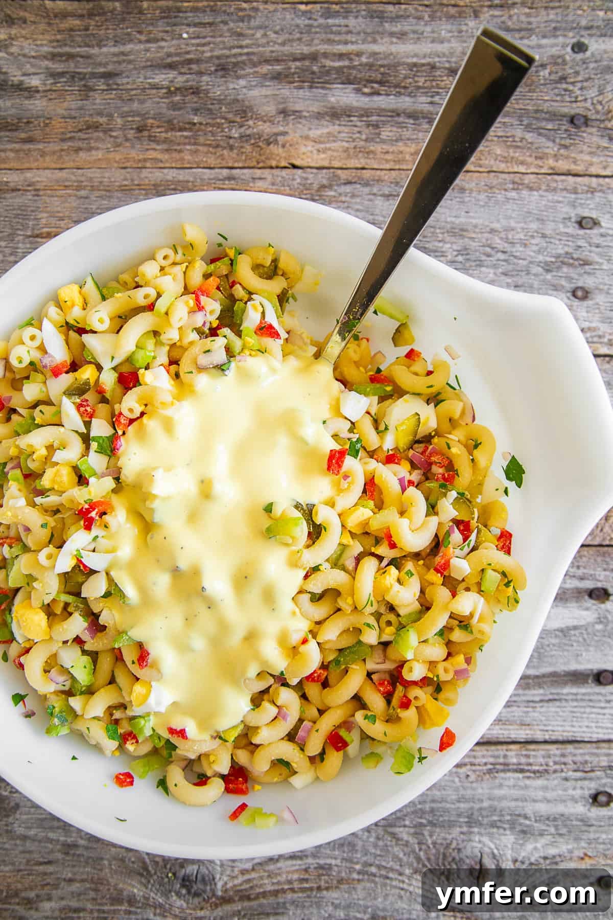 Grandma's Macaroni Salad 6 Classic Macaroni Salad in a bowl with dressing poured generously over the top, ready for mixing.