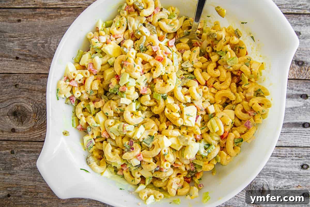 Grandma's Macaroni Salad 7 A serving of Classic Macaroni Salad in a white bowl, garnished with fresh parsley.