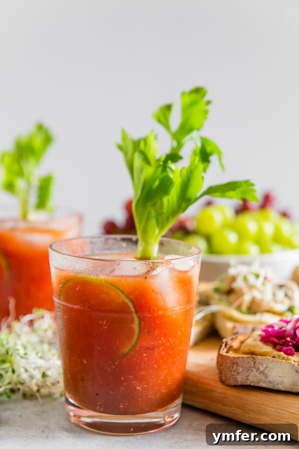 A vibrant Horseradish Bloody Mary cocktail, garnished with a fresh celery stalk and a lime wedge, sitting on a rustic wooden table.