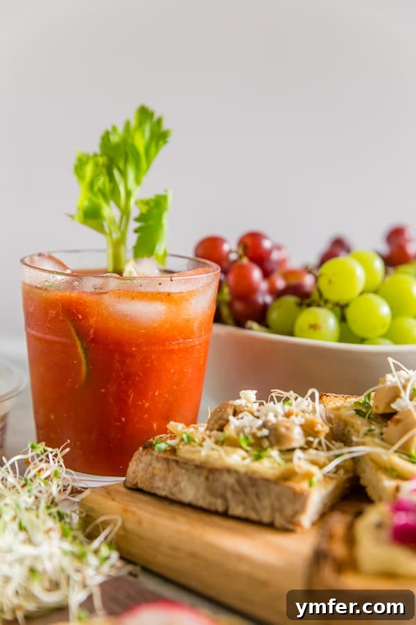 A Horseradish Bloody Mary served in a tall glass, garnished simply with a fresh lime wedge, against a blurred background.