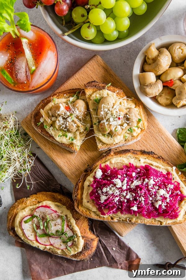 A spread of Horseradish Bloody Mary cocktail and various hummus toasts, creating an inviting brunch scene on a wooden table.