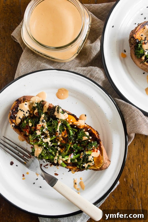 Loaded Sweet Potatoes with Broccoli Rabe and Hummus 2 Two halves of broccoli rabe and hummus stuffed sweet potatoes on a white plate, ready to be eaten with forks.