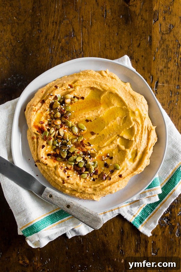 Quick Autumn Pumpkin Hummus 4 A serving platter of pumpkin hummus on a wooden table, surrounded by various dippers.