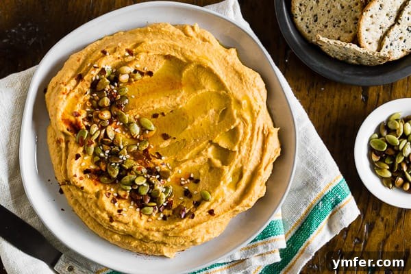 Quick Autumn Pumpkin Hummus 5 A bowl of pumpkin hummus surrounded by various crackers, ready for dipping.