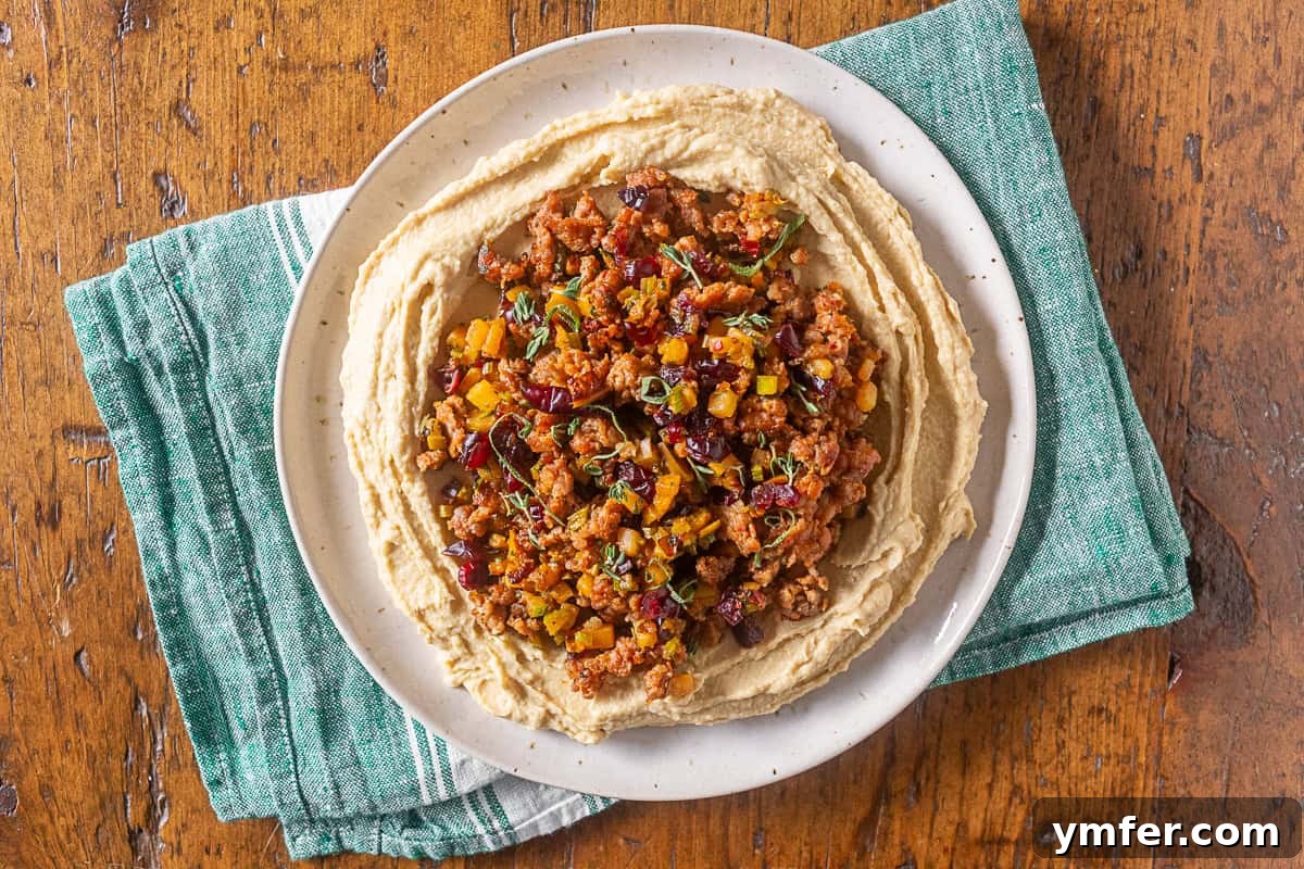 Stuffing Crusted Hummus 5 thanksgiving stuffing topped hummus on a white plate with a green napkin underneath, ready to be served