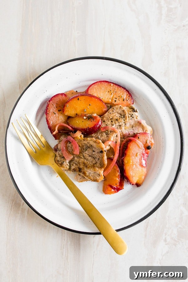 Plum-Glazed Pork Tenderloin Skillet 3 skillet pork tendrloin with plums shot from overhead on a plate with a fork.