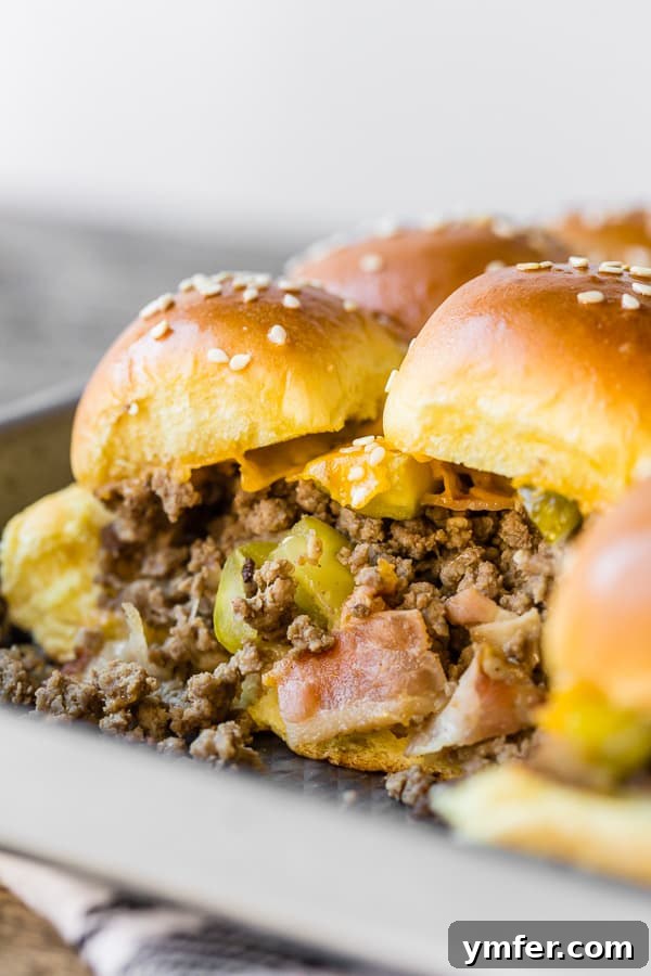 Cheesy Bacon Pull-Apart Sliders 5 A close-up shot showing the inside of a baked bacon cheeseburger slider, revealing the savory meat, melted cheese, and pickles.