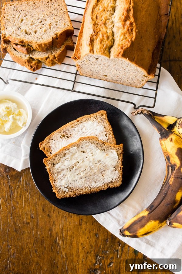 Tangy Sourdough Banana Loaf 2 Sourdough discard banana bread sliced on a plate with butter, showcasing its moist texture and golden-brown crust.