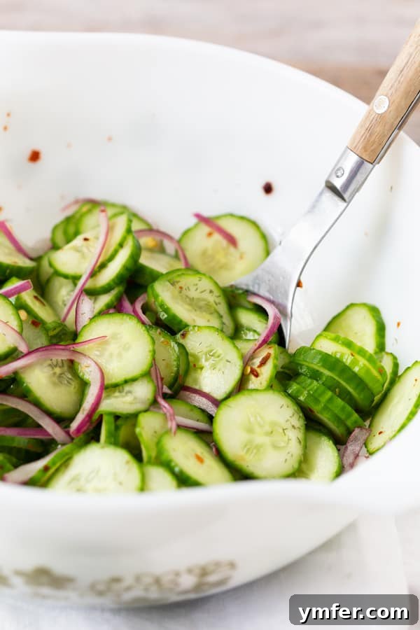 Crisp and Cool Cucumber Salad 4 A large white bowl brimming with fresh cucumber and red onion salad, ready for serving.