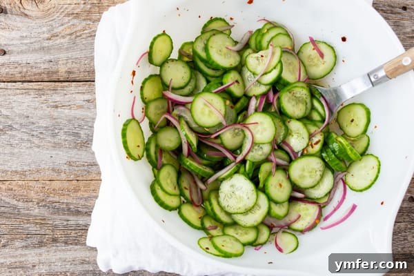 Crisp and Cool Cucumber Salad 7 A large white serving bowl overflowing with refreshing cucumber and red onion salad.