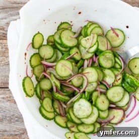 sliced cucumber salad with sliced red onion in a white bowl
